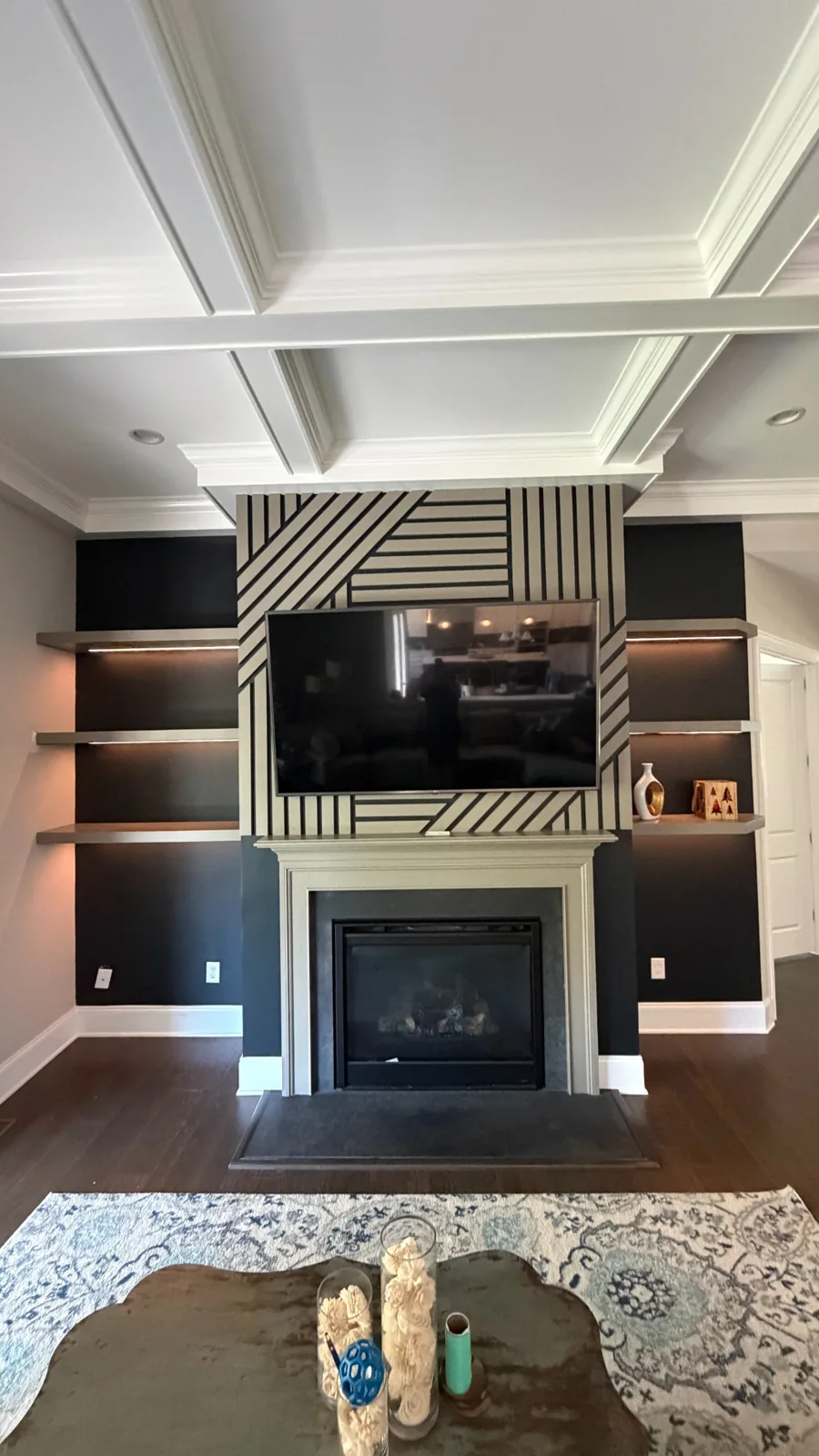 Geometric accent wall around the fireplace and television, with floating shelves