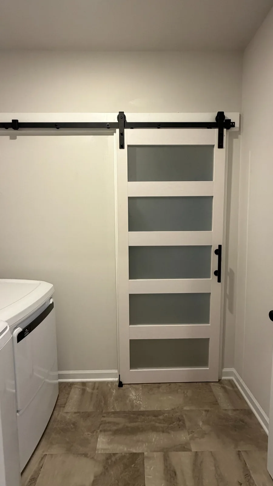 White sliding barn door with frosted glass panels on a black rail
