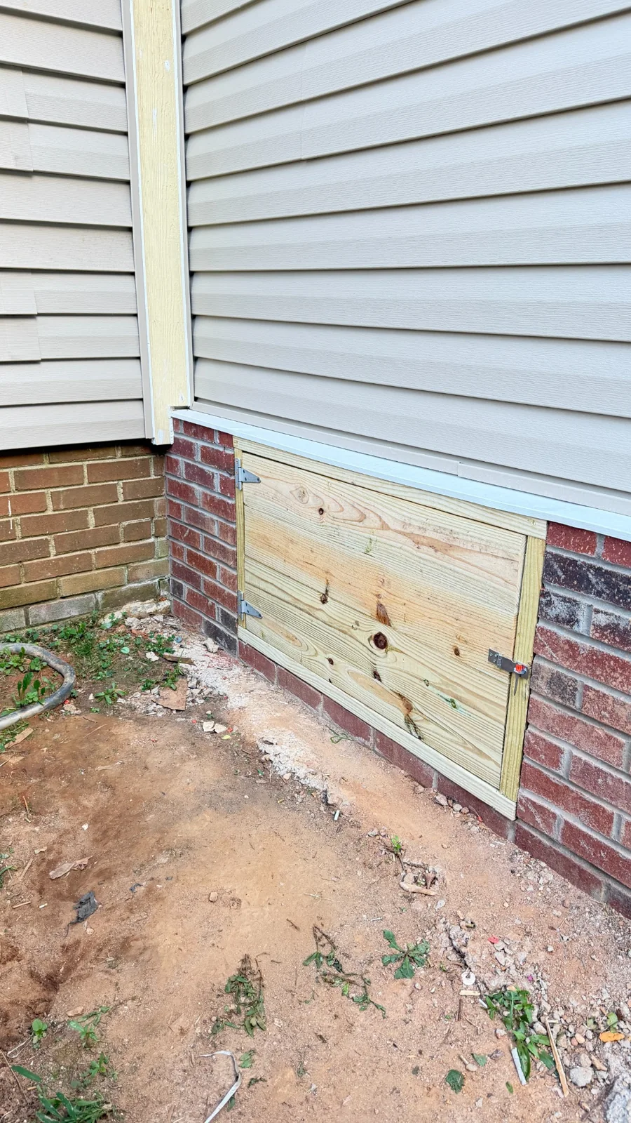 Custom wood crawl space door installed with hinges and a latch