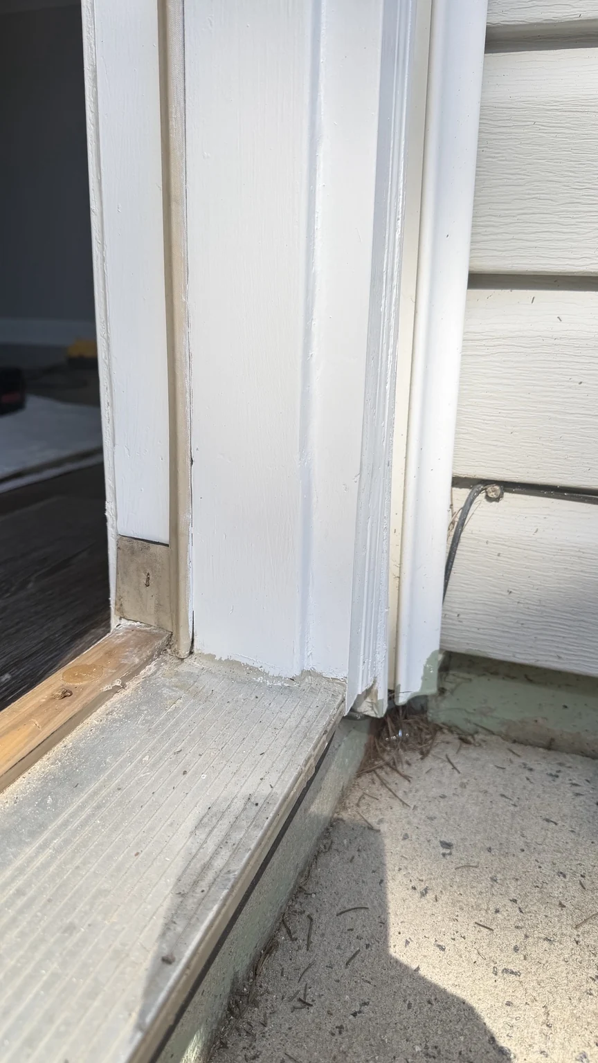 Repaired lower door frame with white painted trim beside the threshold