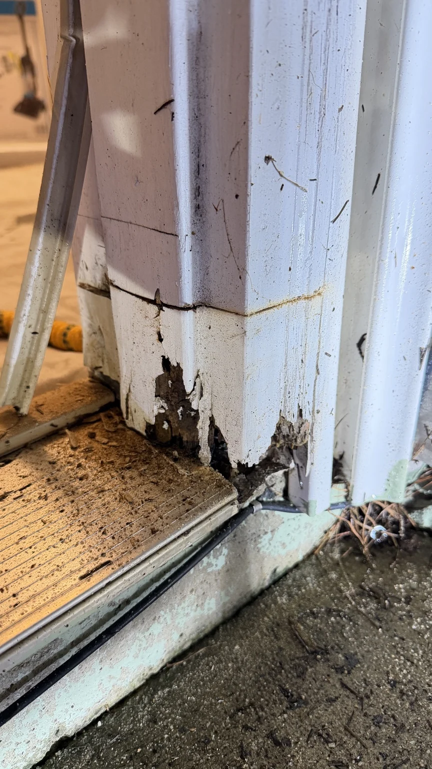 Deteriorated wood and peeling paint at the bottom of an exterior door frame