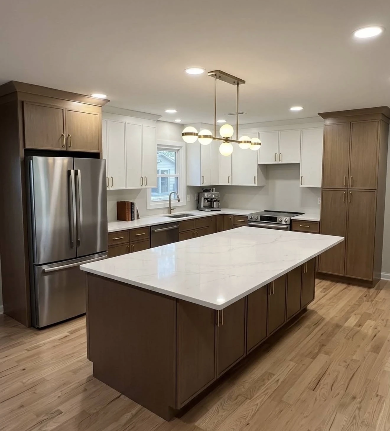 Completed kitchen with white upper cabinets, wood-tone lower cabinets and a large island