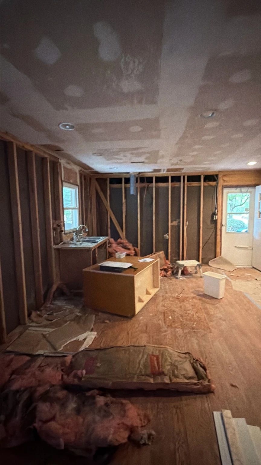Kitchen during demolition with cabinets removed and wall framing exposed
