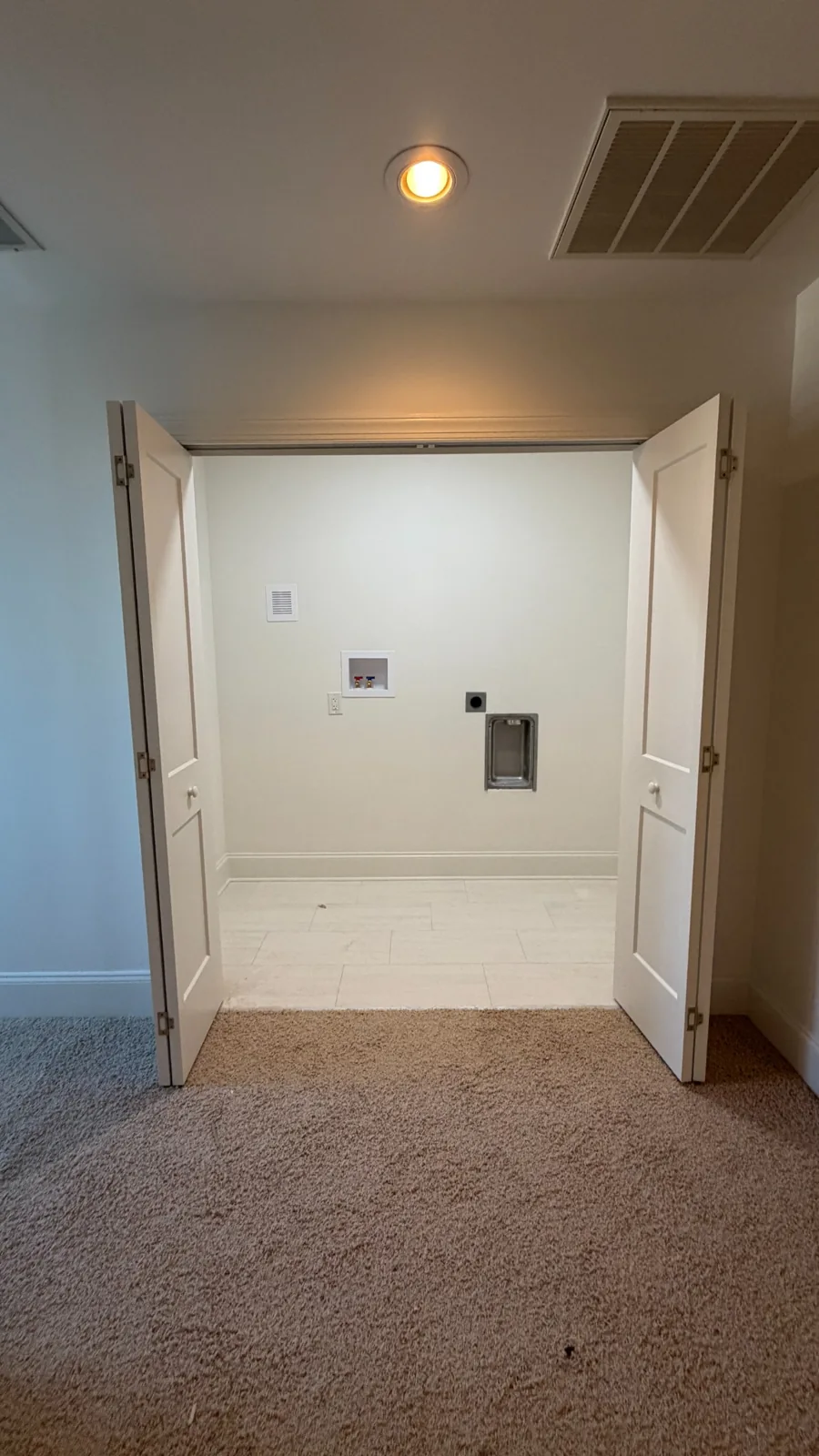Laundry niche with tiled floor, open bifold doors and appliance connections
