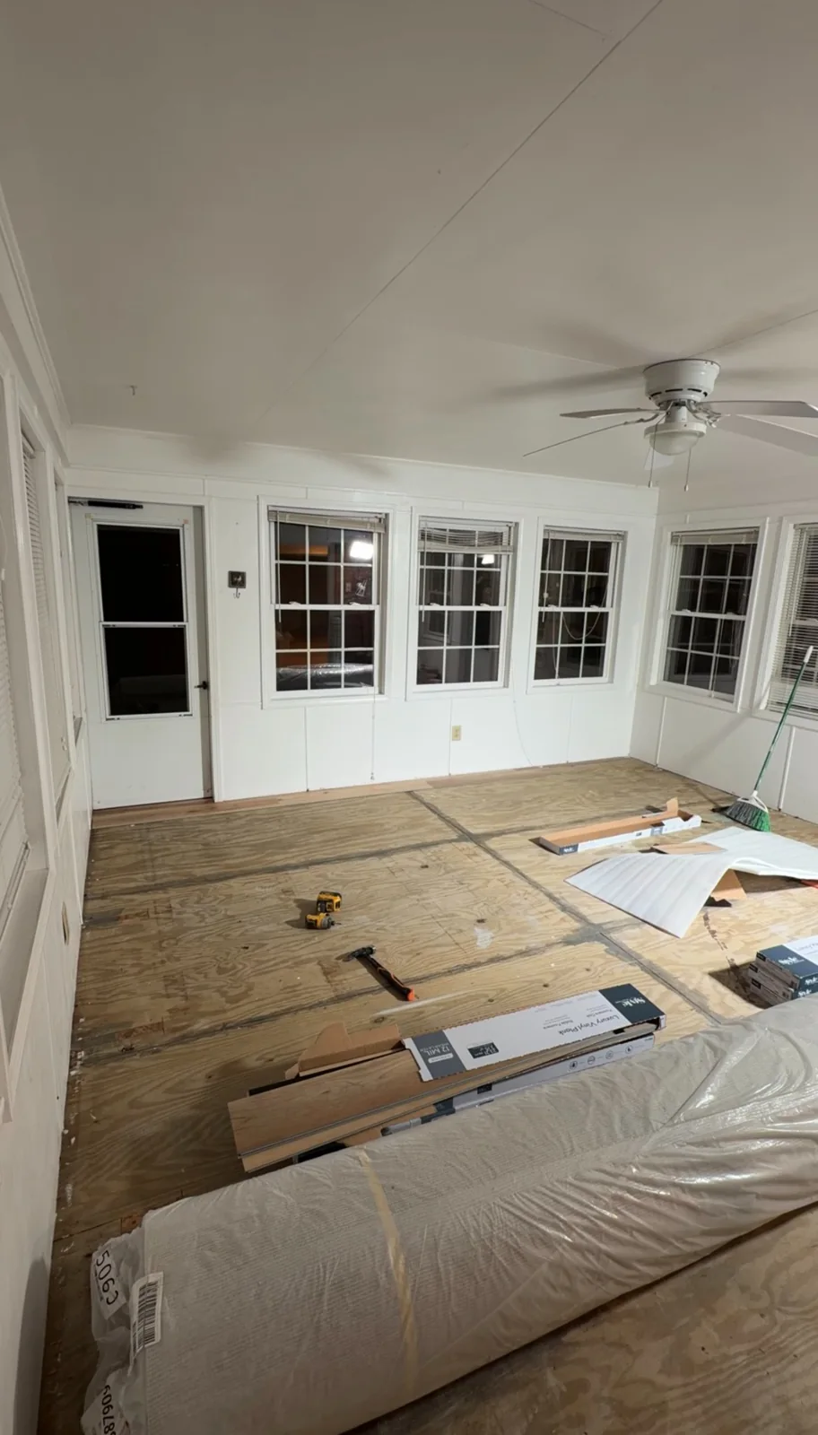 Window-lined room with exposed plywood subfloor before installation